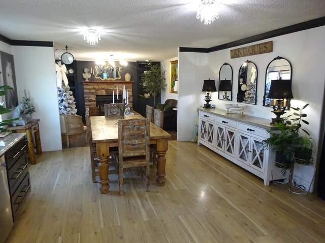 dining room featuring an inviting chandelier, ornamental molding, light wood-style floors, and a textured ceiling