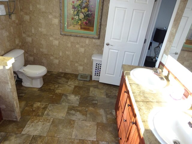 full bathroom featuring vanity, stone finish floor, and toilet