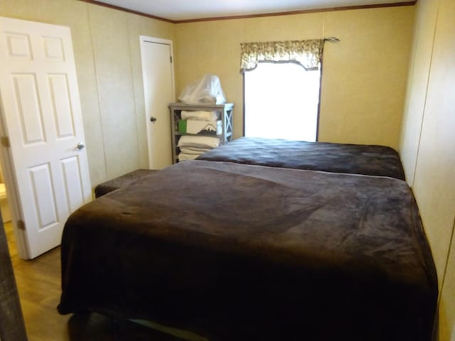 bedroom with wood finished floors and ornamental molding