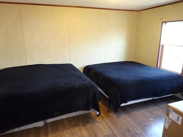 bedroom with crown molding and wood finished floors