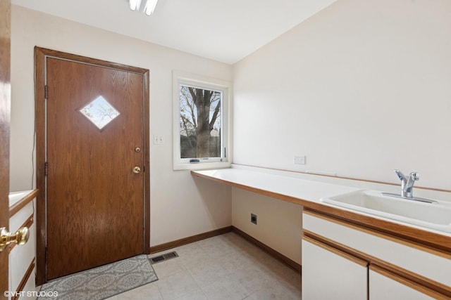 foyer entrance with built in desk, visible vents, and baseboards