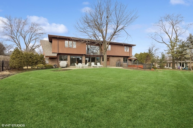 rear view of property with a patio, brick siding, a lawn, and fence