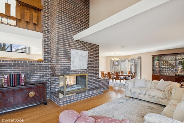 living area with a brick fireplace, wood finished floors, and beamed ceiling