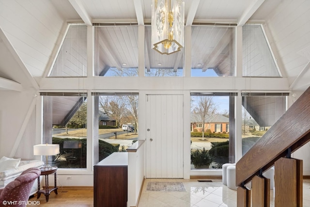 entryway featuring a healthy amount of sunlight, vaulted ceiling with beams, and a notable chandelier