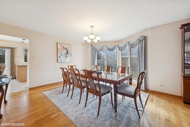 dining room featuring light wood-type flooring, baseboards, and a chandelier