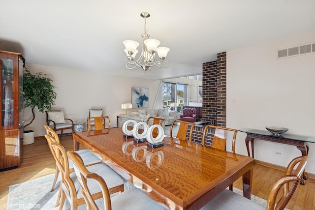 dining area featuring light wood-style floors, baseboards, visible vents, and a chandelier