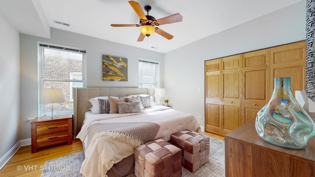 bedroom with baseboards, visible vents, ceiling fan, light wood-type flooring, and a closet