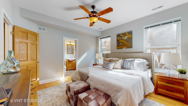 bedroom featuring light wood-type flooring, visible vents, connected bathroom, and baseboards