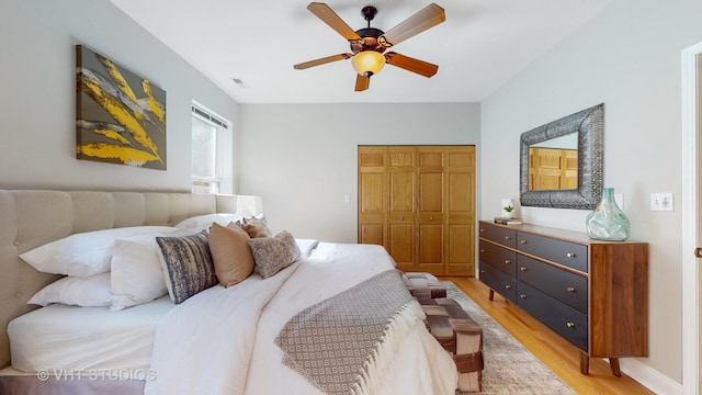 bedroom featuring light wood-style floors, a closet, ceiling fan, and baseboards