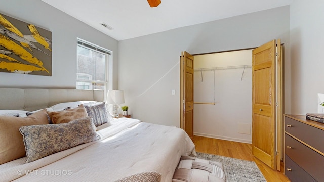 bedroom with light wood finished floors, a closet, visible vents, and a ceiling fan