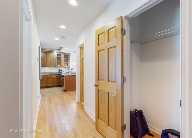 corridor with recessed lighting, a sink, light wood-style flooring, and baseboards