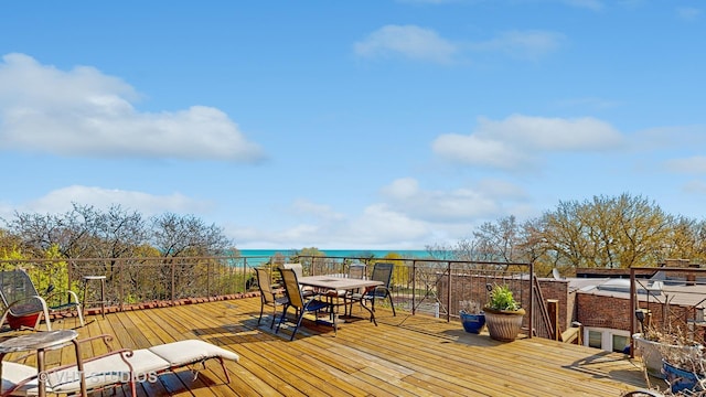 wooden terrace featuring outdoor dining area and a water view