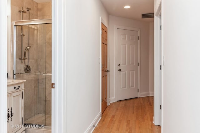 hallway with light wood-type flooring, baseboards, visible vents, and recessed lighting