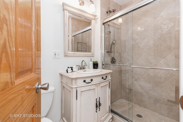 bathroom featuring toilet, a stall shower, and vanity