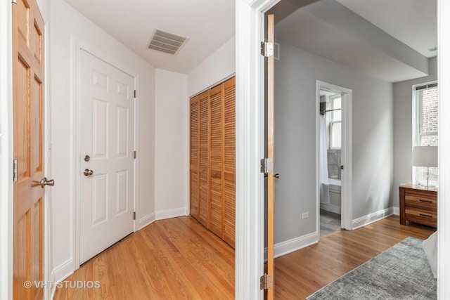 bedroom with light wood-style flooring, visible vents, and baseboards