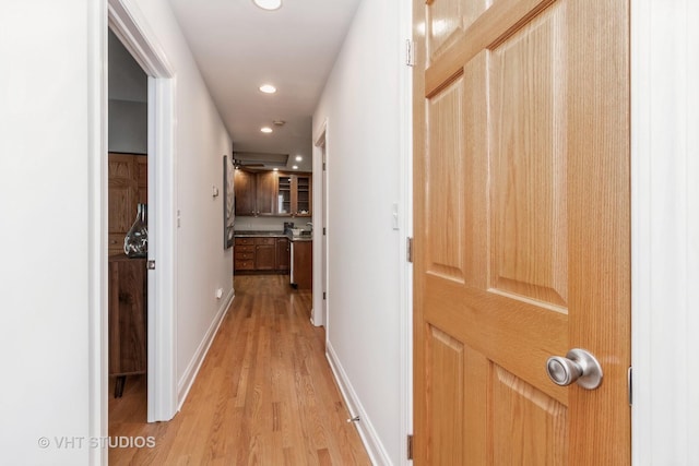 hall featuring light wood-type flooring, baseboards, and recessed lighting