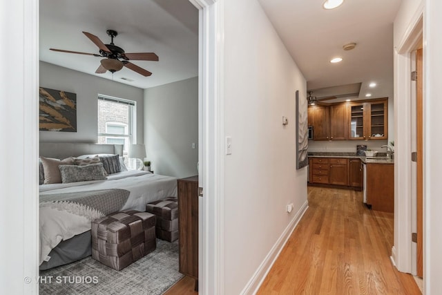 hall featuring recessed lighting, visible vents, a sink, light wood-type flooring, and baseboards