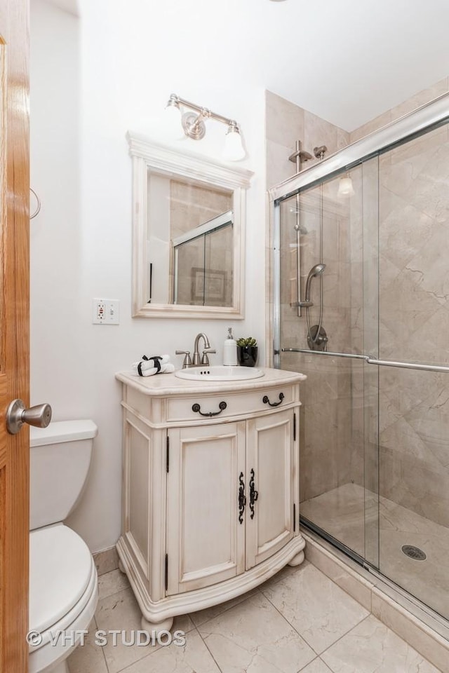 bathroom with marble finish floor, vanity, a shower stall, and toilet