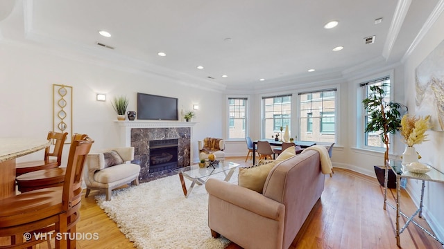 living room featuring recessed lighting, a fireplace, baseboards, light wood-style floors, and crown molding