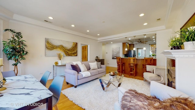 living area featuring light wood-style floors, recessed lighting, visible vents, and crown molding