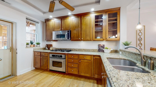 kitchen featuring visible vents, brown cabinetry, light wood-style flooring, appliances with stainless steel finishes, and a sink