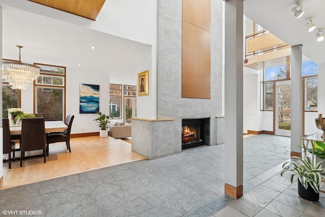 living area with a wealth of natural light, a large fireplace, baseboards, and a high ceiling