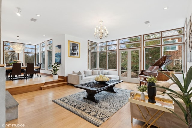 living room featuring french doors, wood finished floors, visible vents, and a notable chandelier