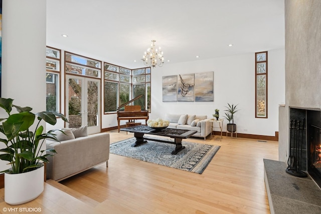 living room featuring a warm lit fireplace, an inviting chandelier, wood finished floors, and recessed lighting