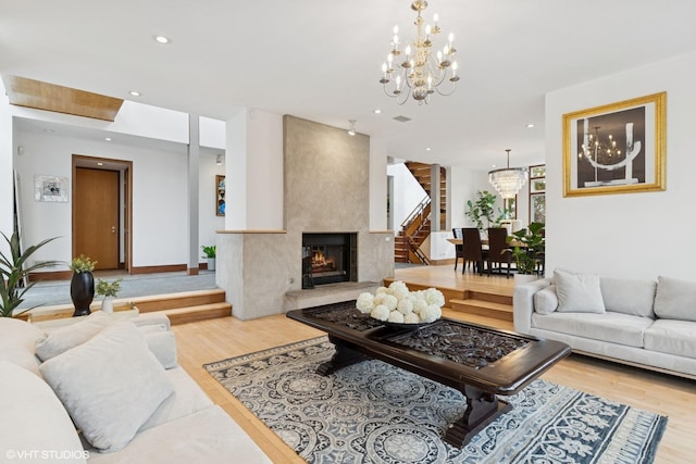 living room with a chandelier, a high end fireplace, wood finished floors, and recessed lighting