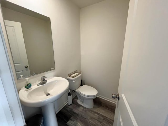 half bath with wood finished floors, toilet, and baseboards