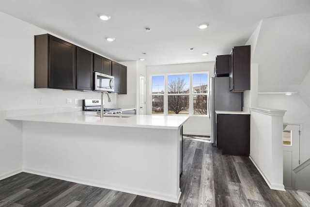 kitchen featuring dark wood-style floors, appliances with stainless steel finishes, light countertops, dark brown cabinets, and a sink