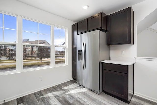 kitchen with light wood-style floors, baseboards, stainless steel refrigerator with ice dispenser, and dark brown cabinets