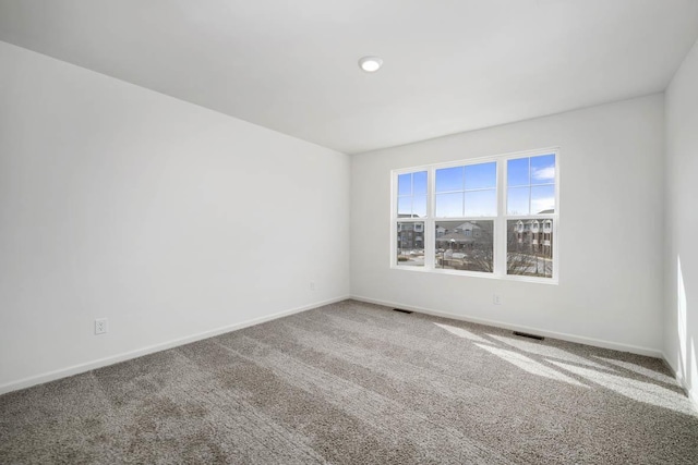 empty room featuring carpet, visible vents, and baseboards