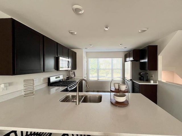 kitchen with stainless steel appliances, a peninsula, a sink, and light countertops