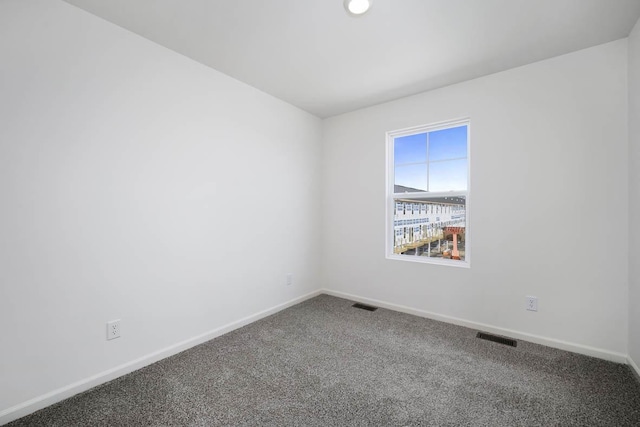 empty room with carpet, visible vents, and baseboards