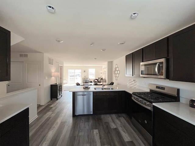 kitchen featuring dark wood finished floors, stainless steel appliances, light countertops, visible vents, and a sink