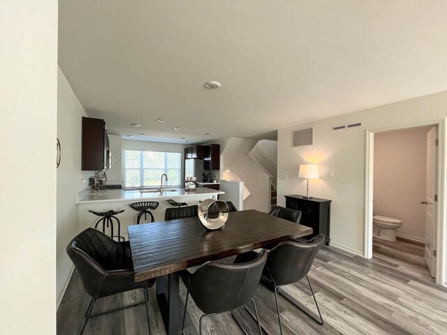 dining area with stairs, baseboards, visible vents, and light wood-style floors