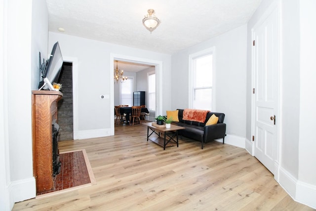 living area with a notable chandelier, plenty of natural light, baseboards, and wood finished floors