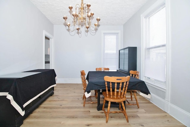 dining space featuring a textured ceiling, baseboards, and wood finished floors