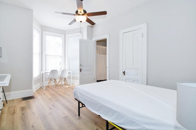 bedroom with multiple closets, visible vents, light wood-style flooring, ceiling fan, and baseboards