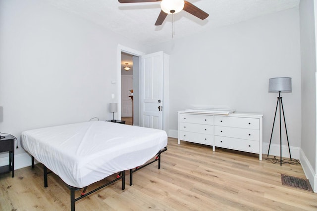 bedroom featuring light wood-style floors, baseboards, visible vents, and ceiling fan