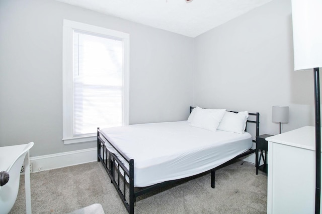 bedroom featuring light carpet and baseboards