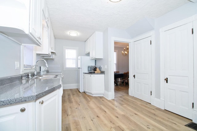 kitchen featuring a textured ceiling, light wood-style flooring, and white cabinets