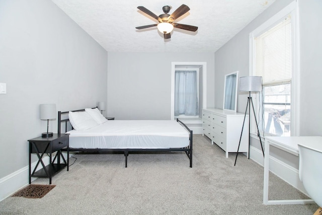 bedroom with light carpet, a textured ceiling, a ceiling fan, and baseboards