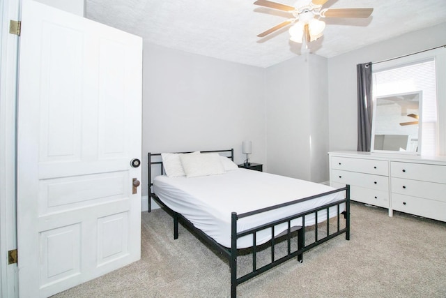 bedroom featuring ceiling fan, a textured ceiling, and light colored carpet