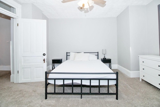 bedroom with light carpet, a textured ceiling, and baseboards