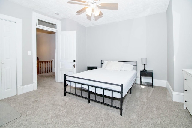 bedroom featuring light carpet, ceiling fan, a textured ceiling, and baseboards