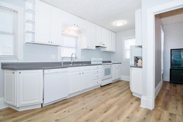 kitchen featuring white appliances, dark countertops, a sink, and white cabinets