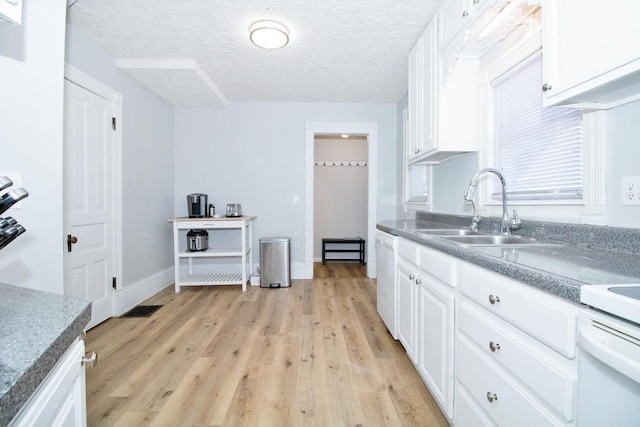 kitchen featuring dishwasher, a sink, light wood-style flooring, and white cabinets