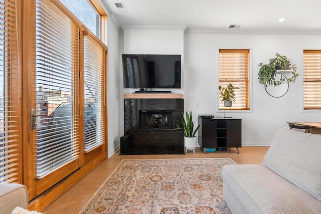 living area featuring baseboards, visible vents, wood finished floors, and ornamental molding